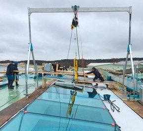 Zwei Arbeiter montieren mit einem SCHILLING Aluminium-Portalkran Dachfenster auf dem Flachdach eines Firmengebäudes.