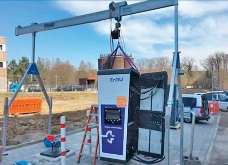 Ein SCHILLING-Alu-Portalkran hebt eine EnBW-Ultraschnellladesäule während der Montage an einem Außenstandort.