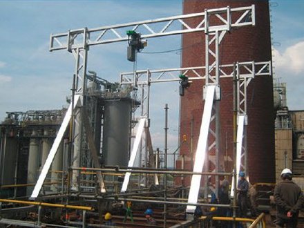 Aluminium-Portalkran von SCHILLING im Einsatz auf einem Industriegelände, im Vordergrund sind Arbeiter mit Schutzhelmen zu sehen.