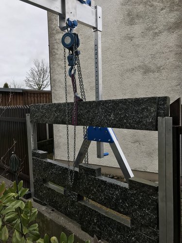 Eine Gartenmauer aus Stein wird mit einem SCHILLING Alu-Portalkran aufgebaut.