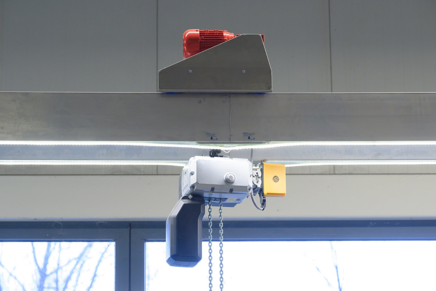 Elektrische Laufkatze von SCHILLING mit Motor, Steuerbox und Kettenmechanismus, montiert an einer Alu-Traverse.